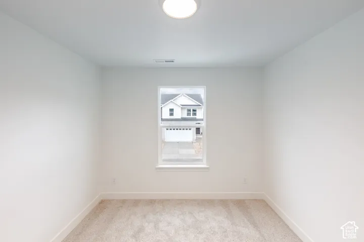 Neutral-toned wall finish, wall-to-wall carpeting, single-pane window with white trim, and a flush-mount overhead light fixture