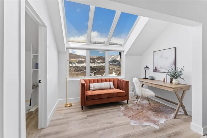 Room featuring multiple skylights, large window with mountain scenery, and wood-finish flooring