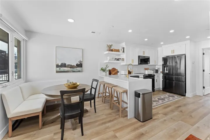 Contemporary kitchen and dining area featuring light wood-finish flooring
