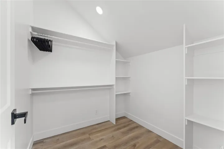 Attic closet featuring wood-finish flooring and integrated shelving