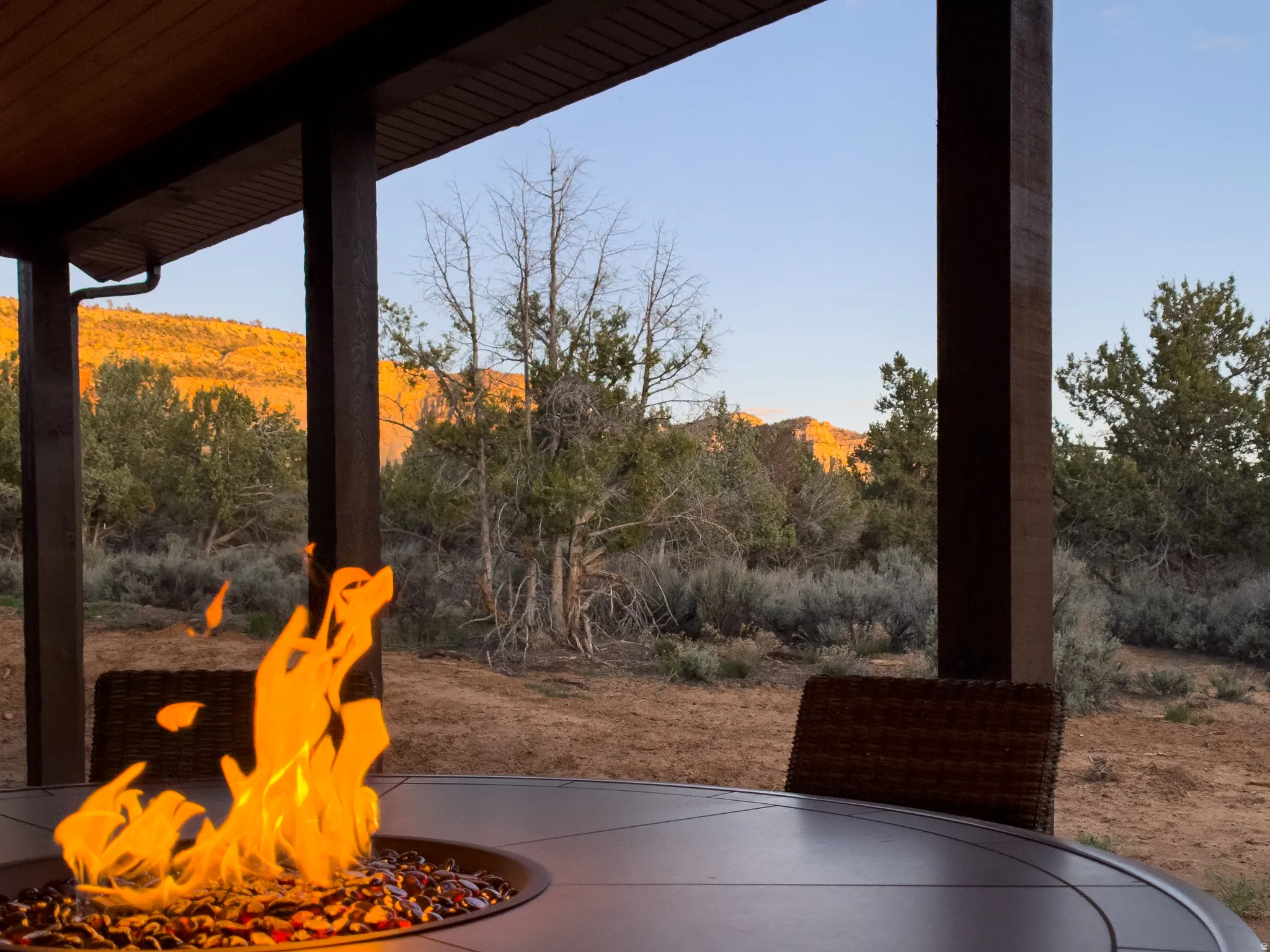 Covered patio featuring a built-in fire pit, plank ceiling, and structural wood columns