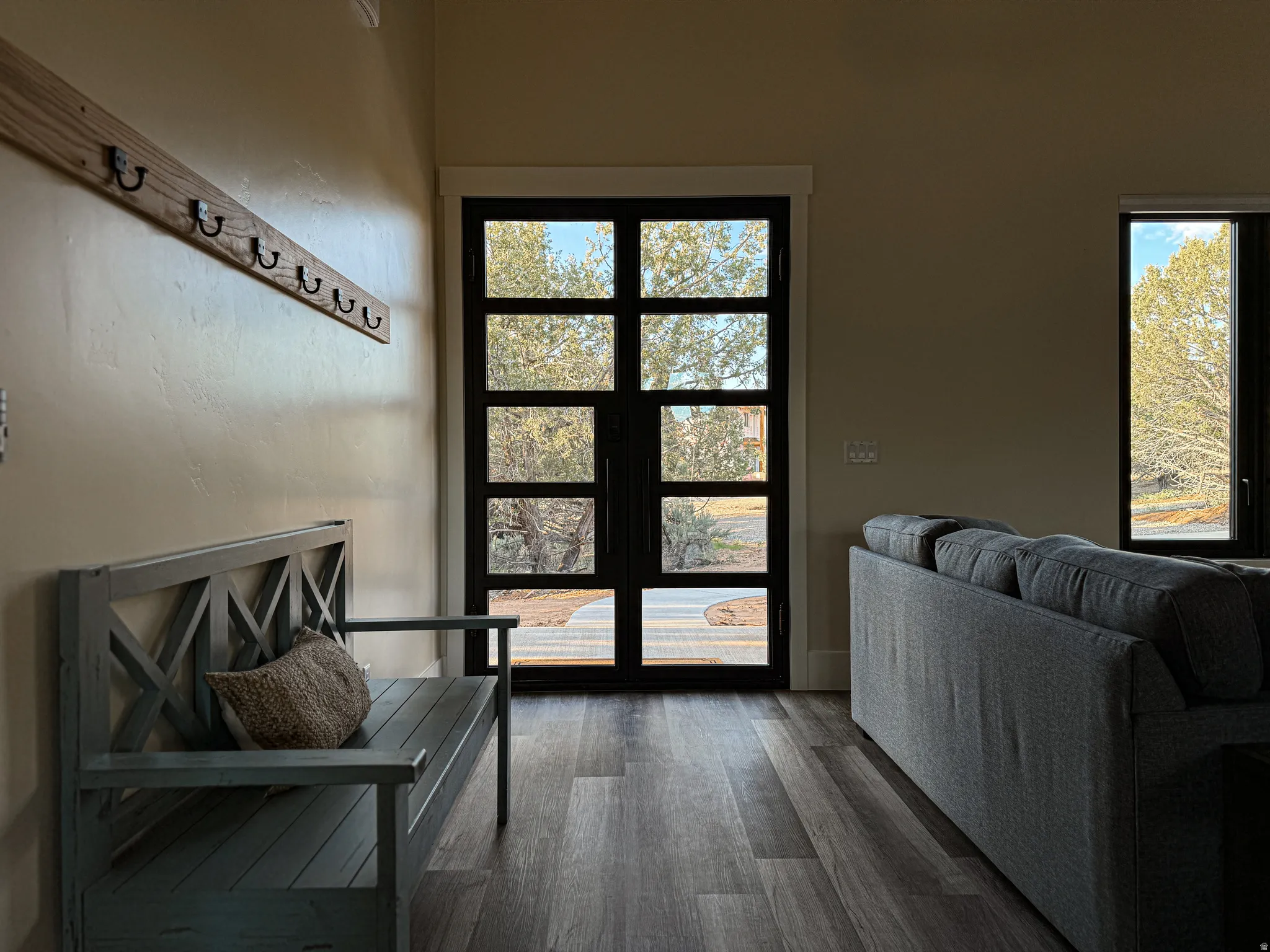 Entryway featuring a multi-paneled glass door with dark trim, wood-finish flooring, and a built-in wall-mounted coat rack