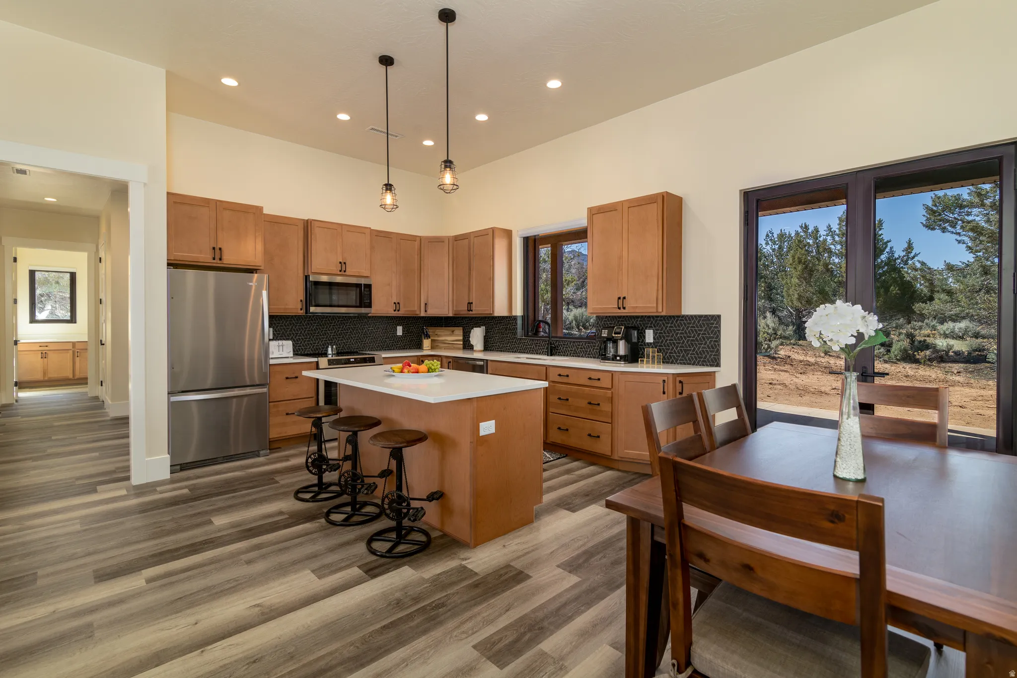 Open-concept kitchen with wood-finish cabinetry, stainless steel appliances, a center island with countertop seating, and recessed lighting