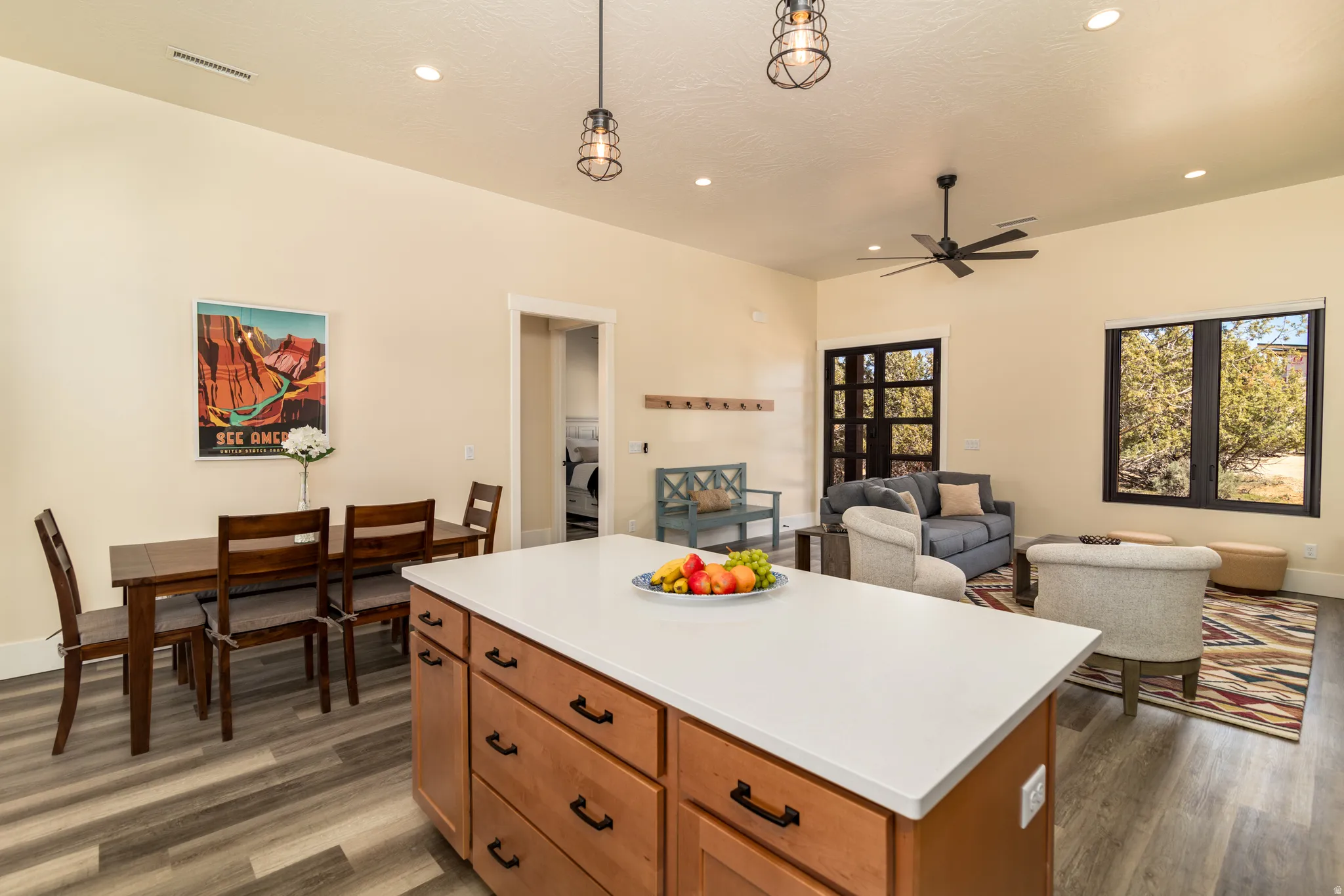 Open-concept living area featuring a kitchen island with a light-colored countertop, wood-finish flooring, recessed lighting, and a ceiling fan