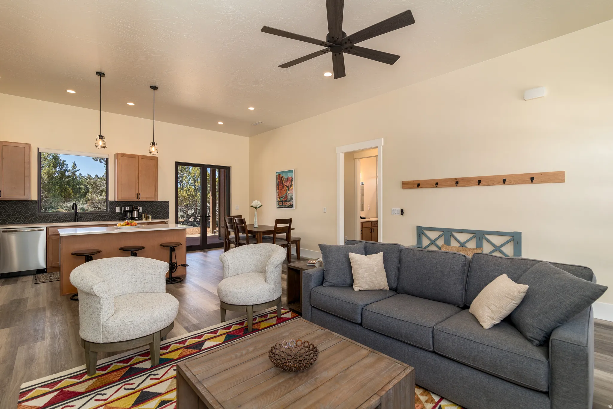Open-concept living area featuring wood-finish flooring, a contemporary ceiling fan, recessed lighting, and a kitchen island with pendant lighting