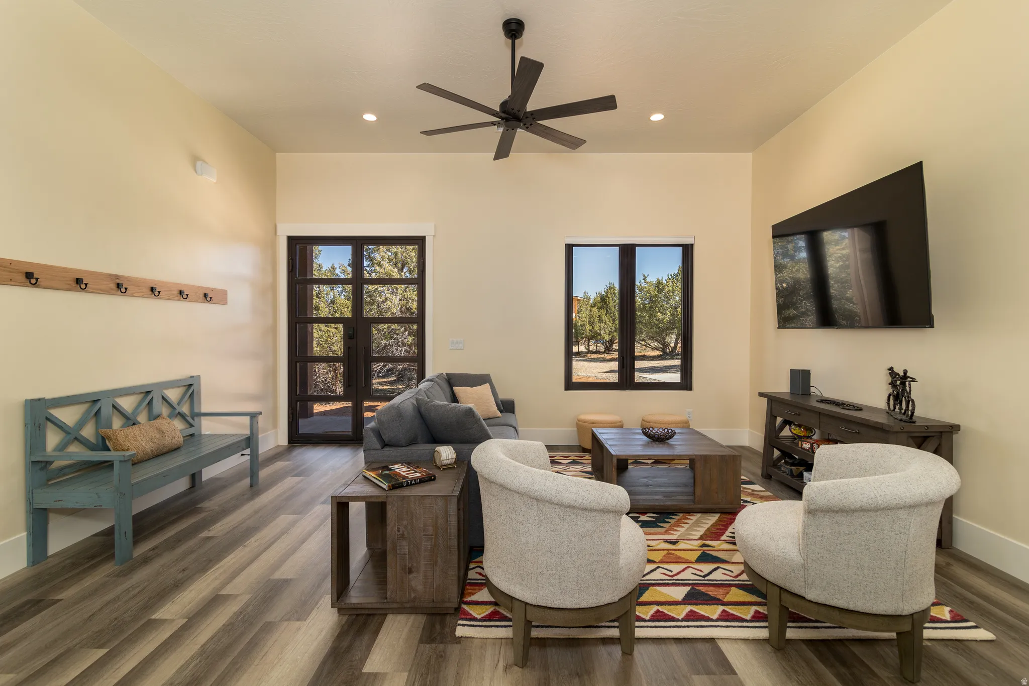 Spacious living area featuring wood-finish flooring, recessed lighting, and a dark-toned ceiling fan