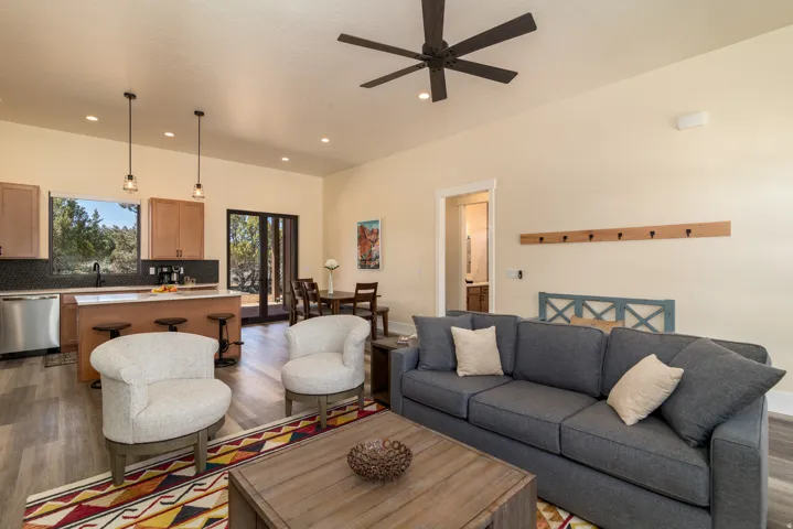 Open-concept living area featuring wood-finish flooring, a contemporary ceiling fan, recessed lighting, and a kitchen island with pendant lighting
