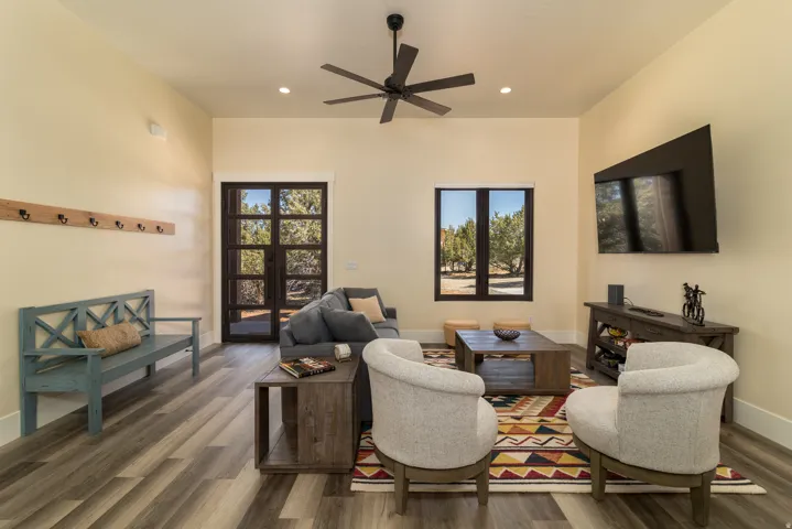 Spacious living area featuring wood-finish flooring, recessed lighting, and a dark-toned ceiling fan