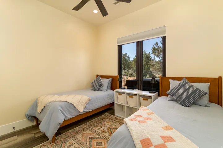 Bedroom 3 with wood-finish flooring, a large window, and a ceiling fan