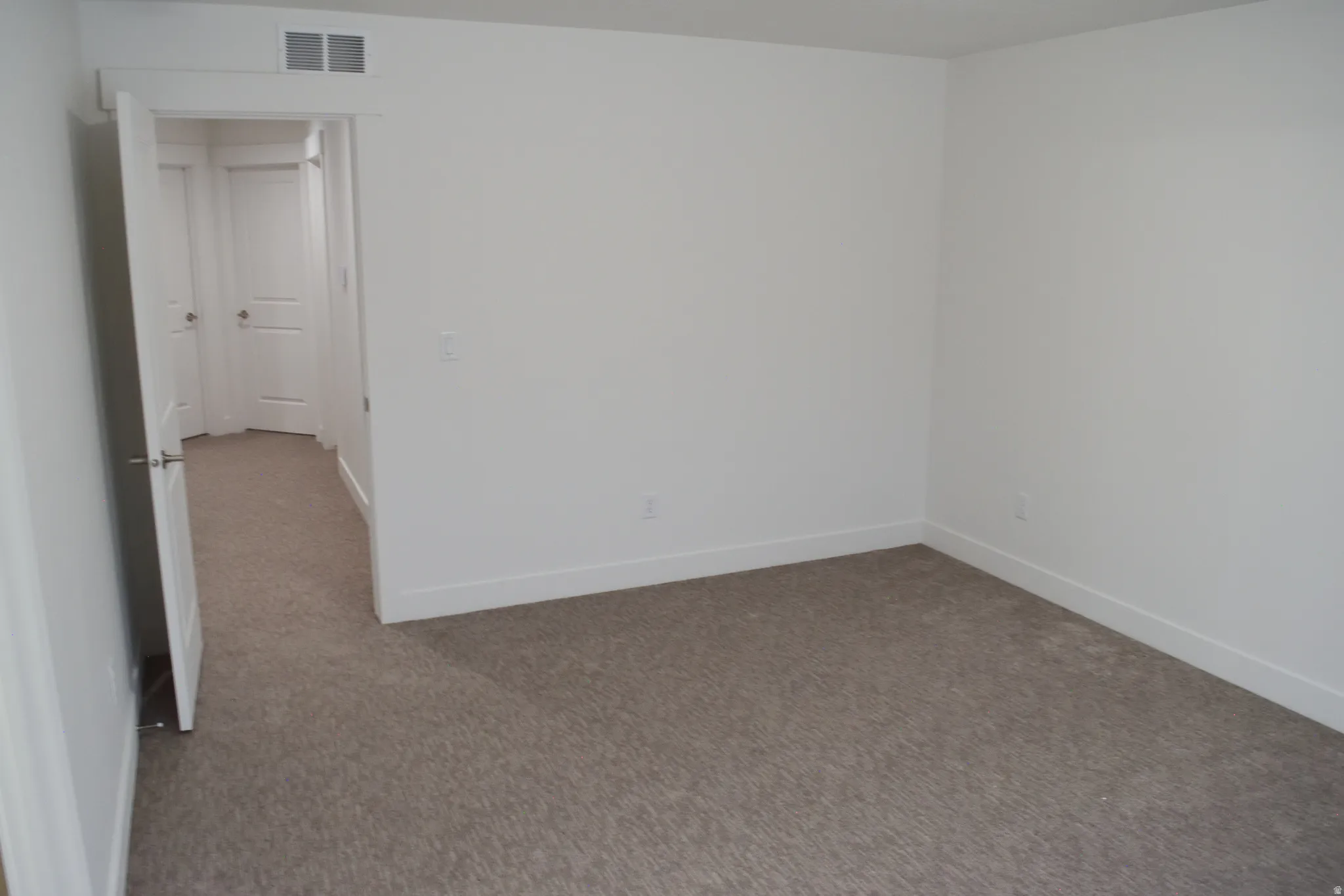 Neutral tone carpet flooring with white baseboards and walls
