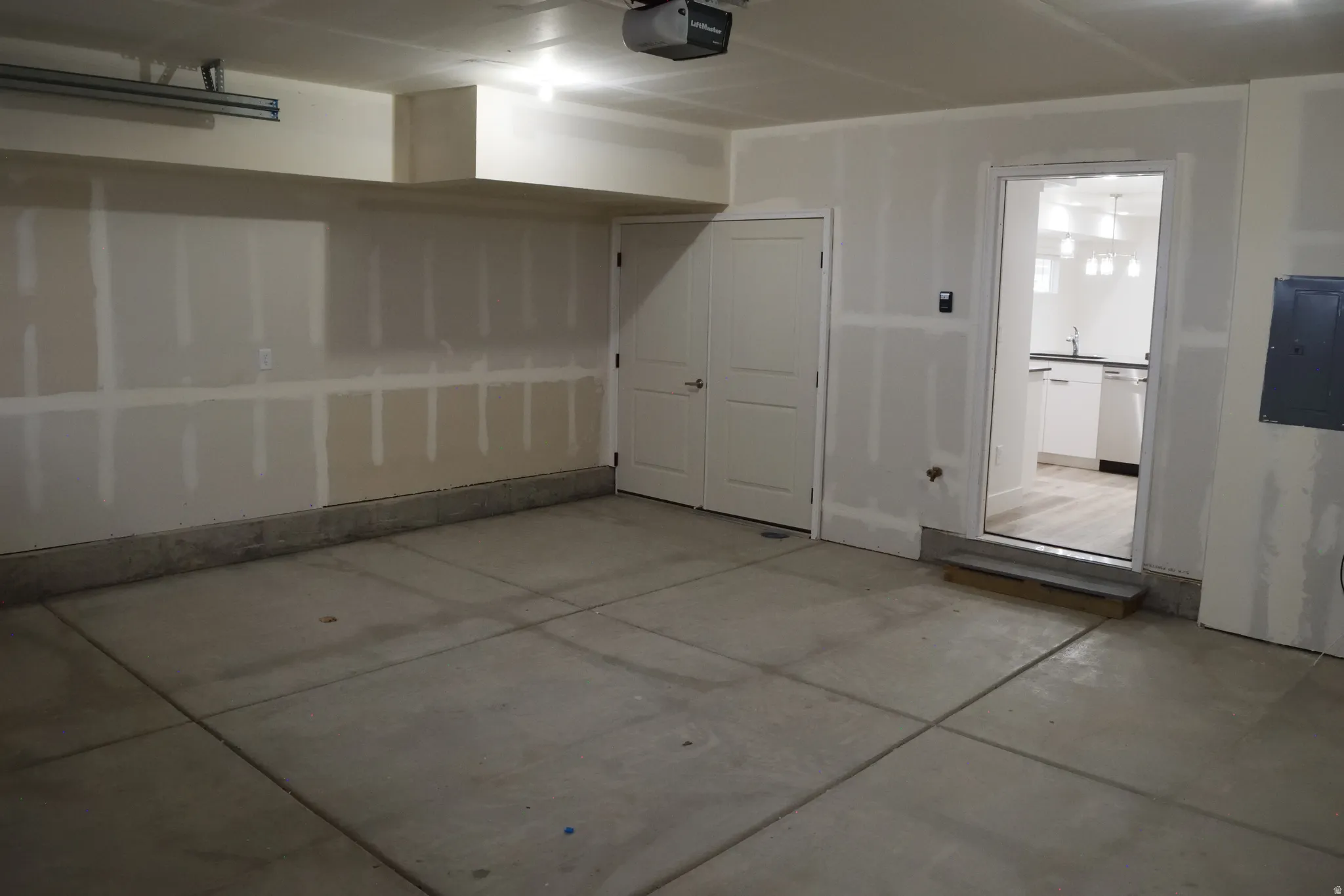 Spacious garage featuring a concrete floor, overhead lighting, and two interior access doors