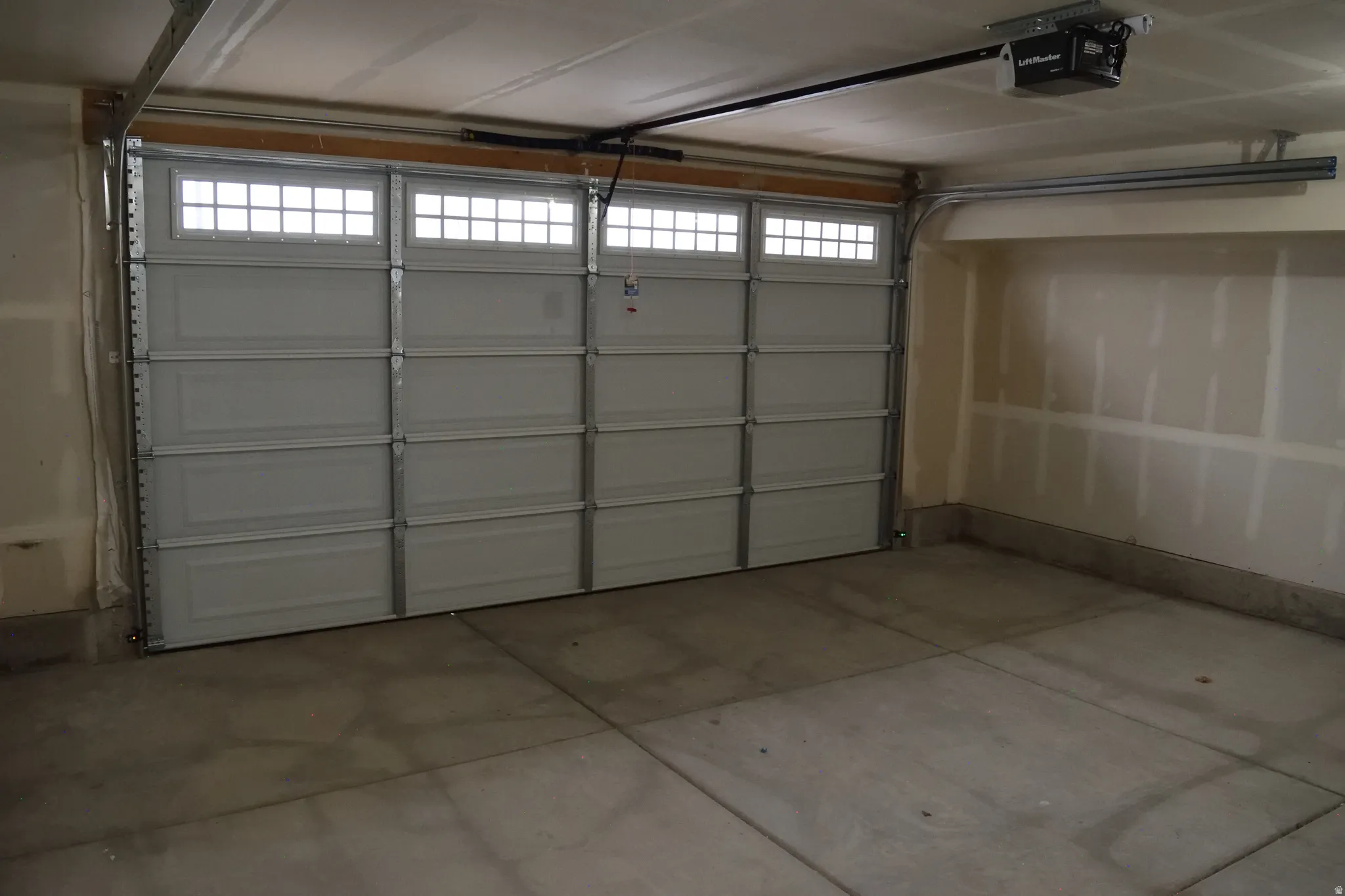 Spacious garage featuring a concrete floor, a paneled garage door with transom windows, and an automatic garage door opener