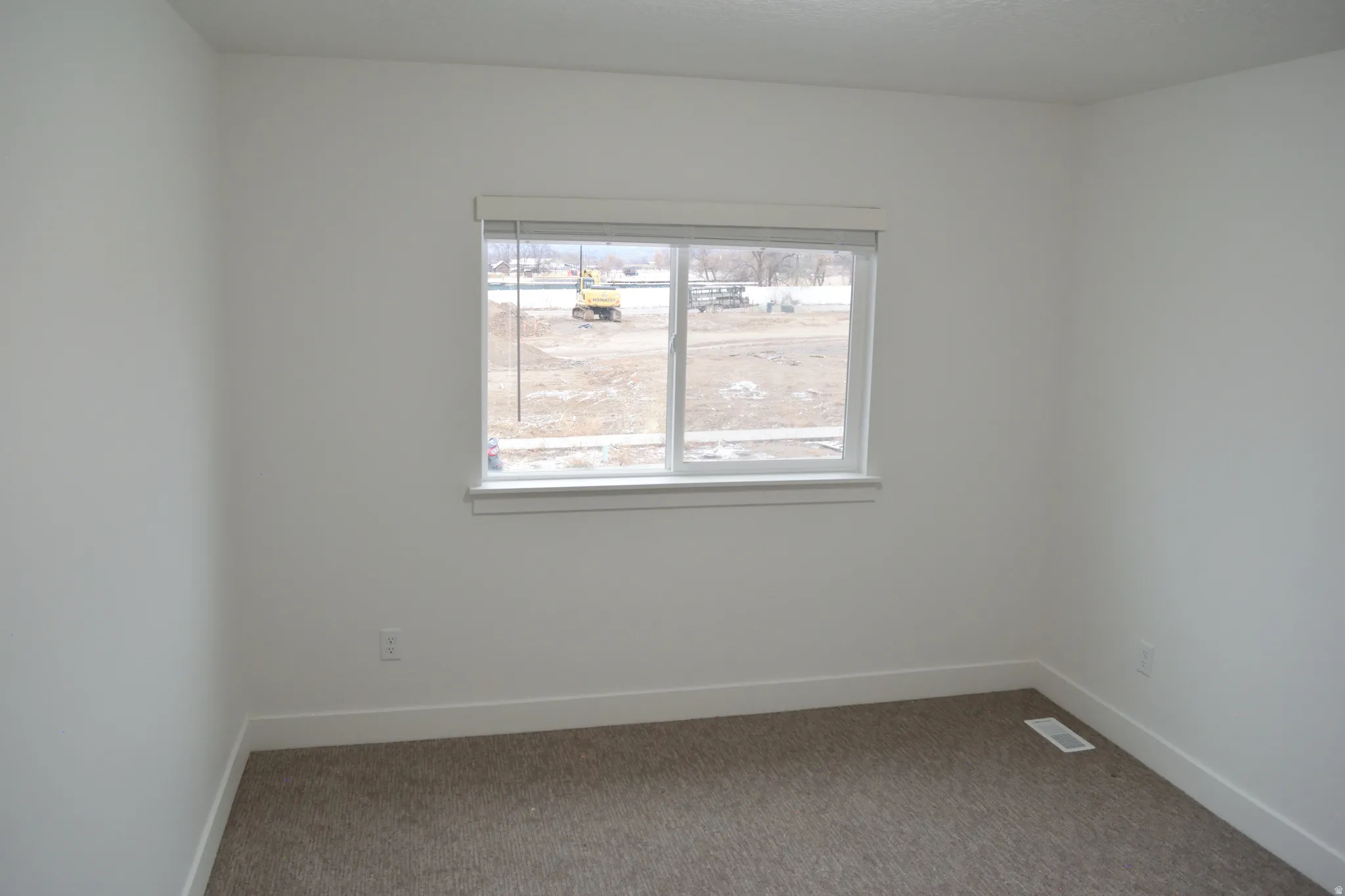 White walls define this room featuring neutral-toned carpet flooring and a single window with white trim