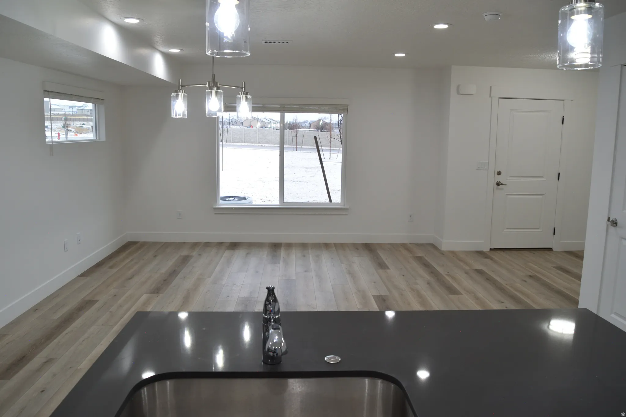 Open-concept living area featuring wood-finish flooring, recessed lighting, and a modern chandelier
