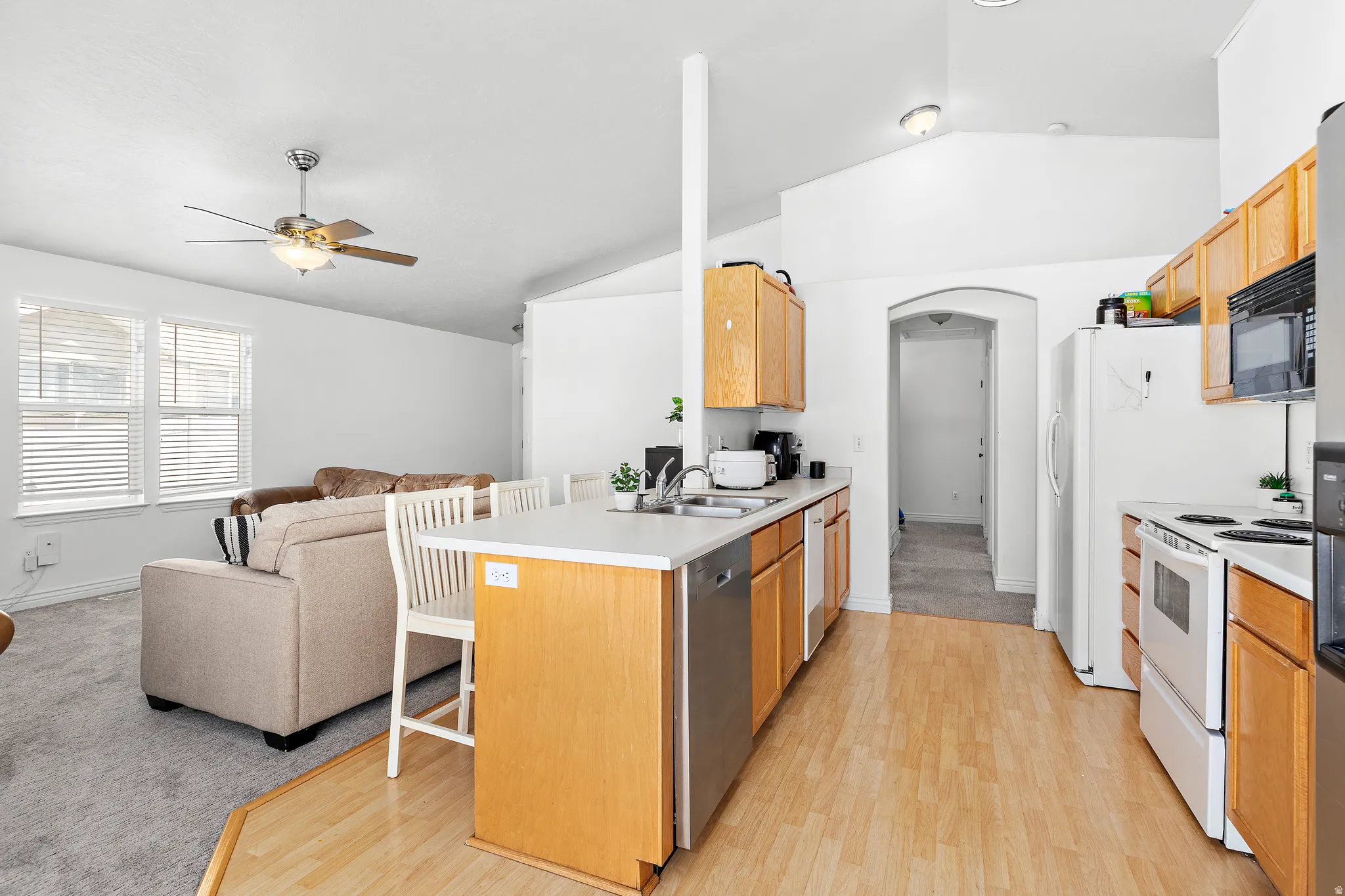 Open-concept kitchen featuring light wood cabinetry, a peninsula with seating, and wood-finish flooring