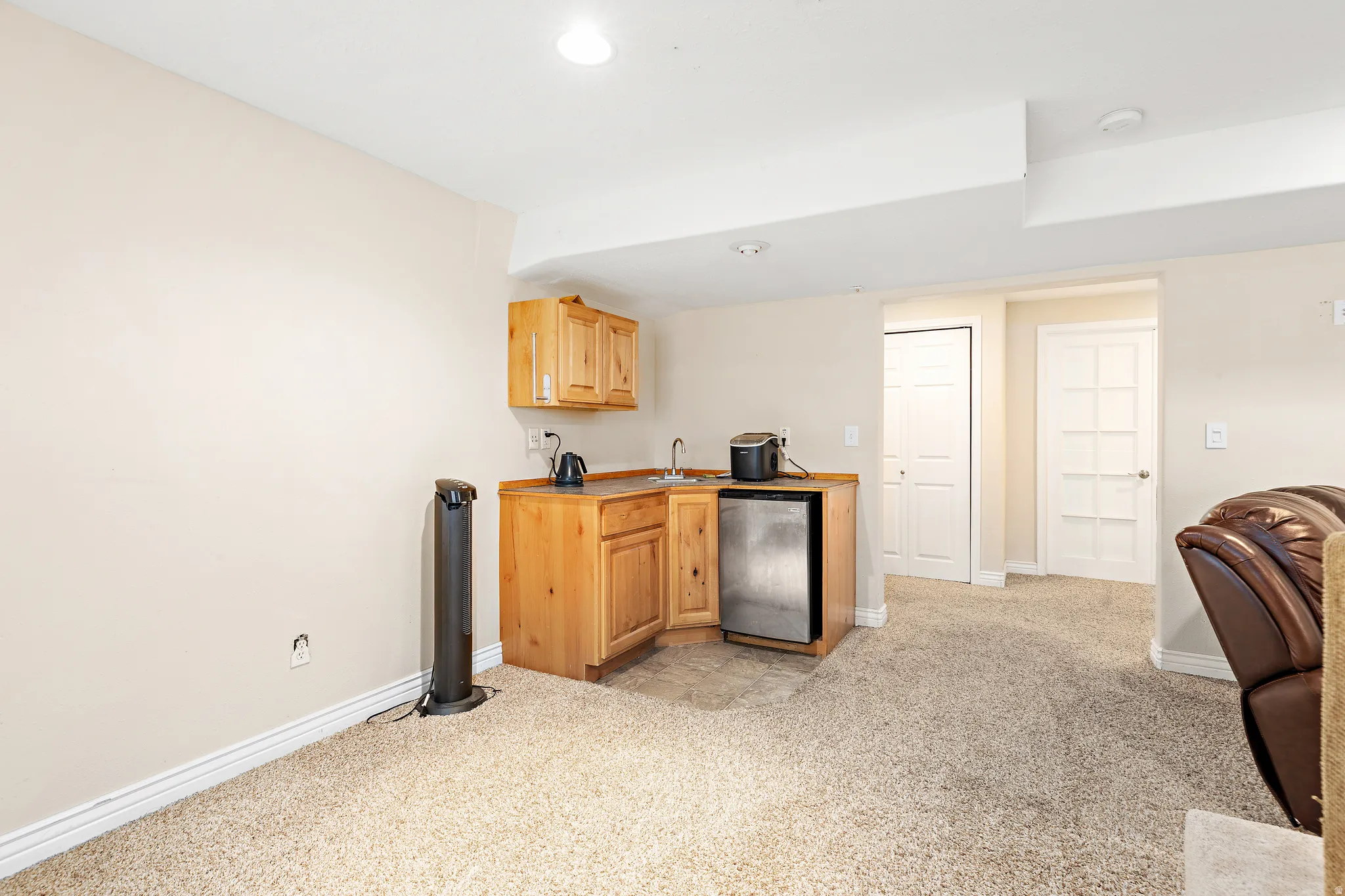 Wet bar featuring natural wood cabinetry, a stainless steel compact refrigerator, and a stainless steel sink with a gooseneck faucet