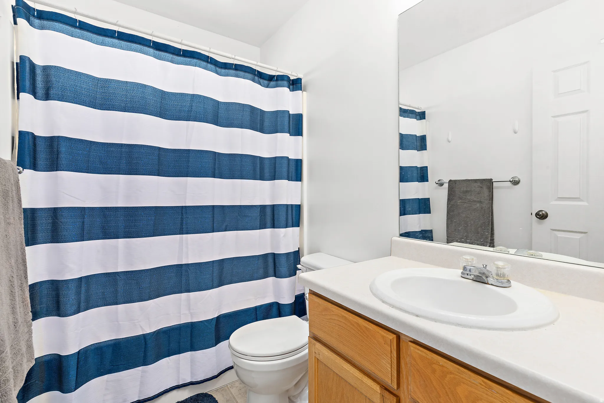 Full bathroom featuring a single-sink vanity with wood-finish cabinetry, a white countertop, and an integrated basin