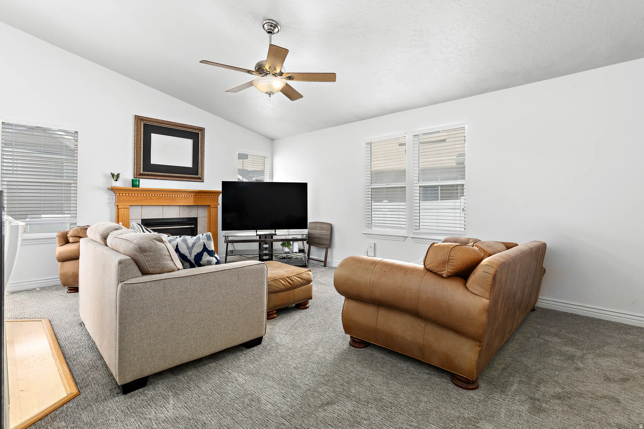 Spacious living area featuring a vaulted ceiling and a ceiling fan with integrated lighting