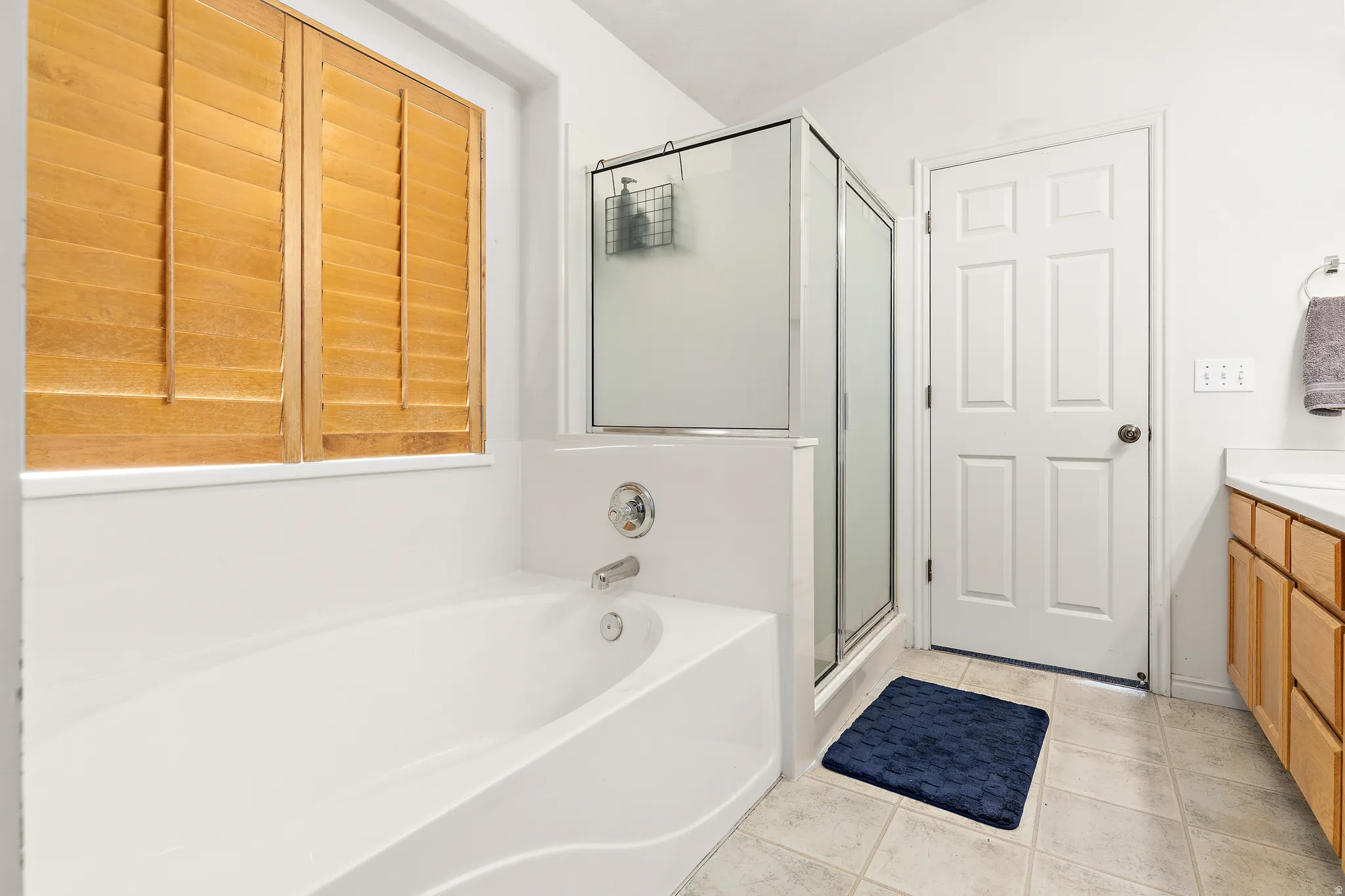 Soaking tub with chrome fixtures and natural wood window shutters