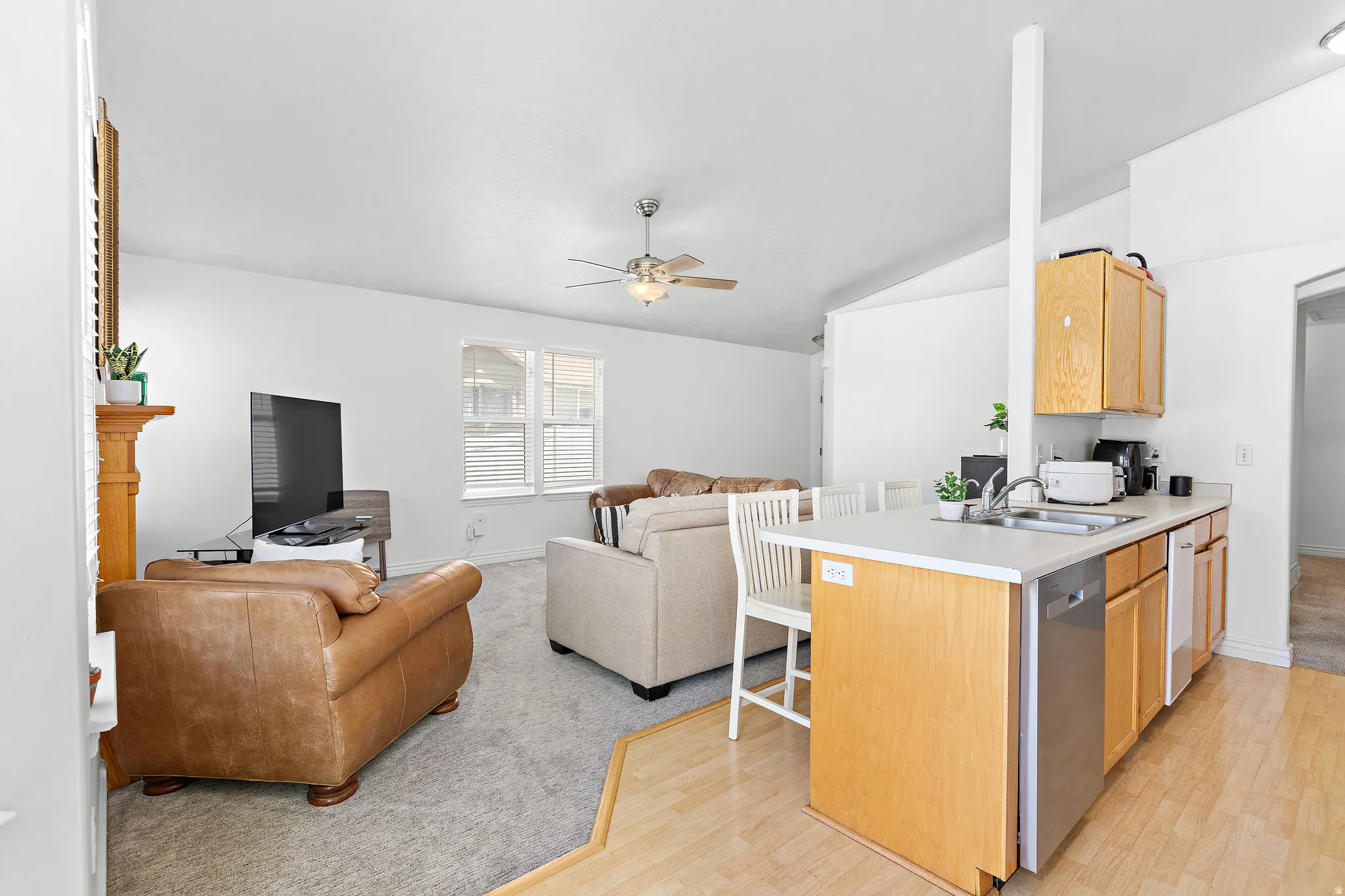 Kitchen island with light wood cabinetry, a stainless steel sink, and a dishwasher