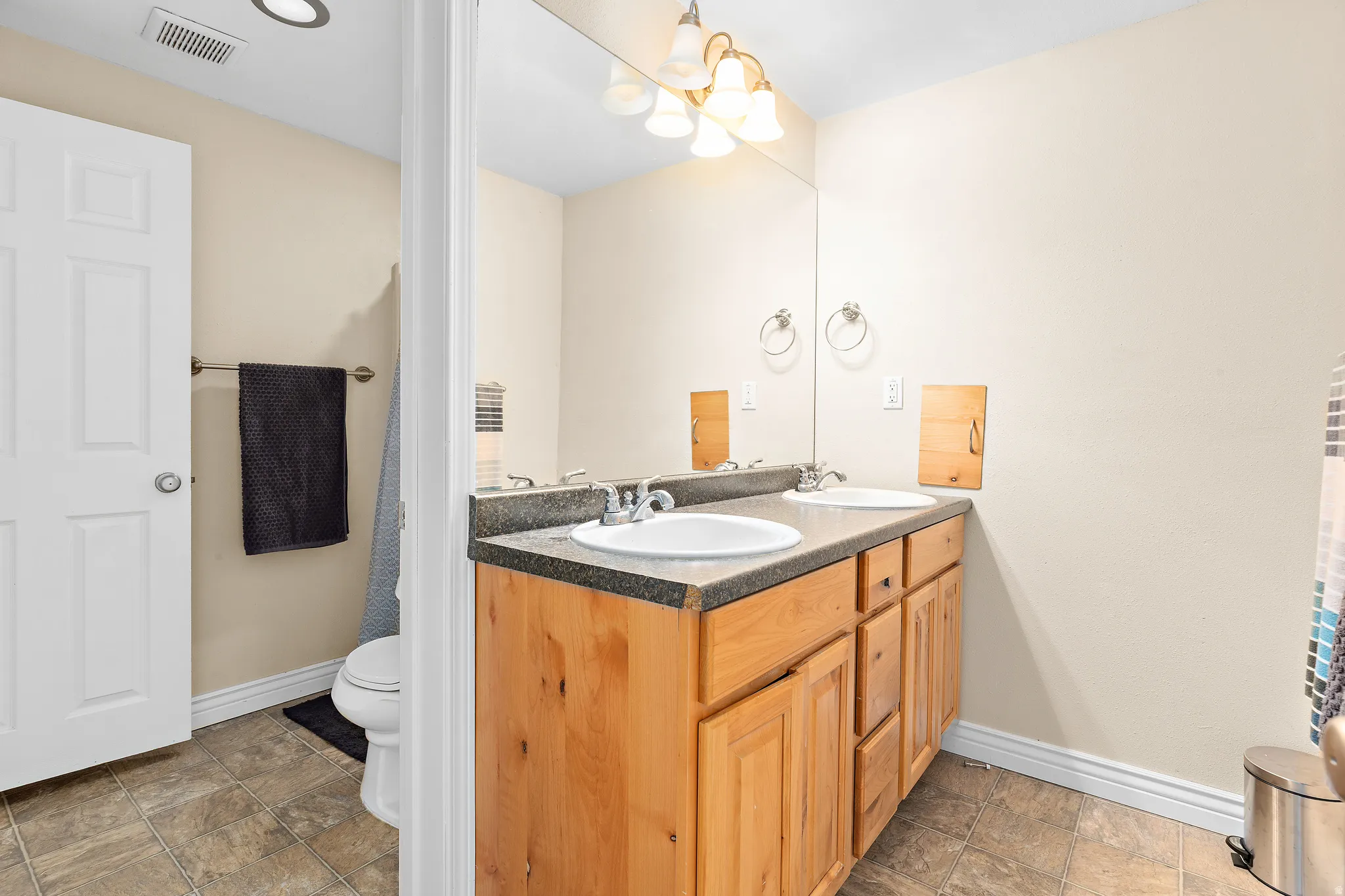 Double vanity featuring wood-finish cabinetry, integrated sinks, and a dark countertop