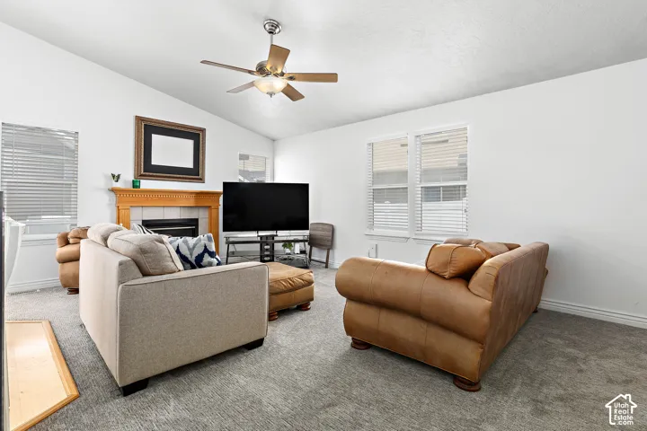Spacious living area featuring a vaulted ceiling and a ceiling fan with integrated lighting