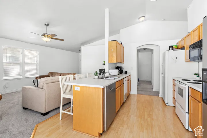 Open-concept kitchen featuring light wood cabinetry, a peninsula with seating, and wood-finish flooring