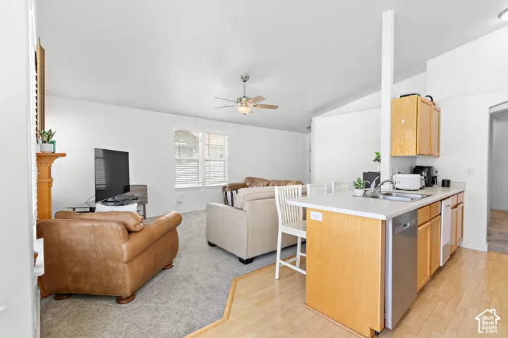 Kitchen island with light wood cabinetry, a stainless steel sink, and a dishwasher
