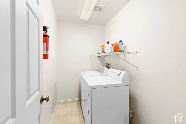 Dedicated laundry area featuring a washer and dryer set, neutral wall paint, and a wall-mounted wire shelving unit for storage
