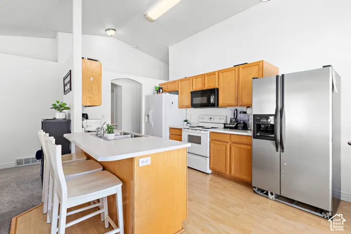 Kitchen featuring wood-finish flooring, light wood cabinetry, white countertops, and vaulted ceilings