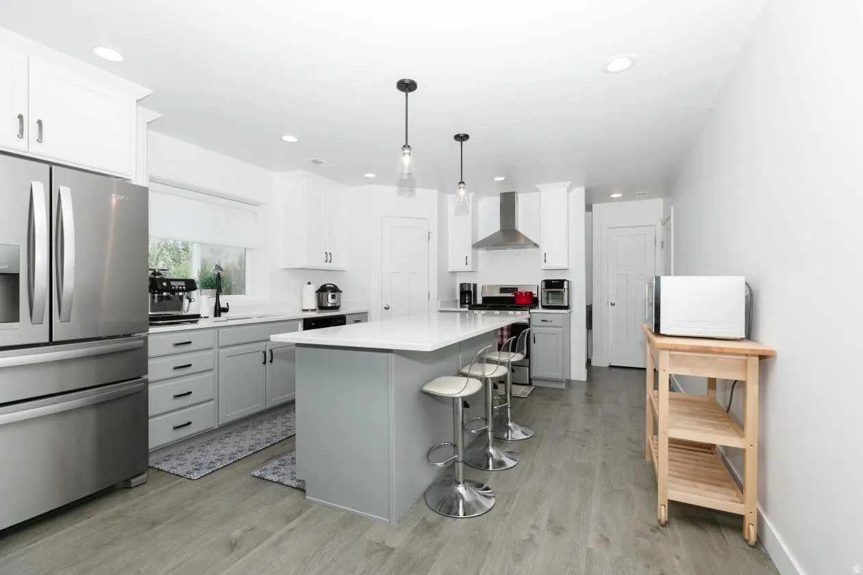 Bright kitchen featuring wood-finish flooring and a central island with countertop seating