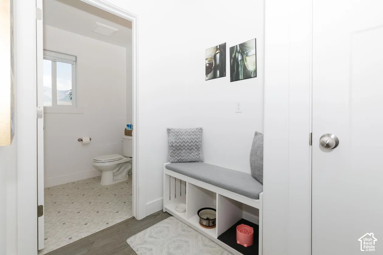 Spacious bathroom featuring a toilet, a window with exterior views, and patterned tile flooring right off of kitchen with a 1\2 bath