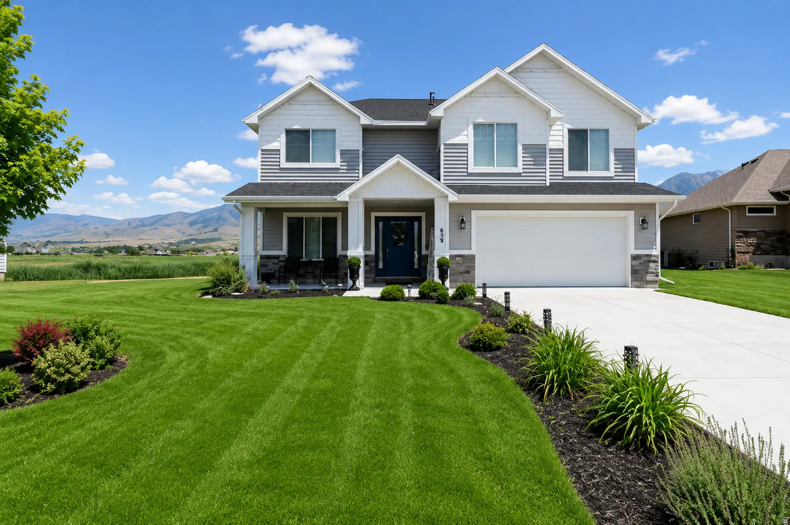 Two-story residence featuring a gray and white exterior with stone accents
