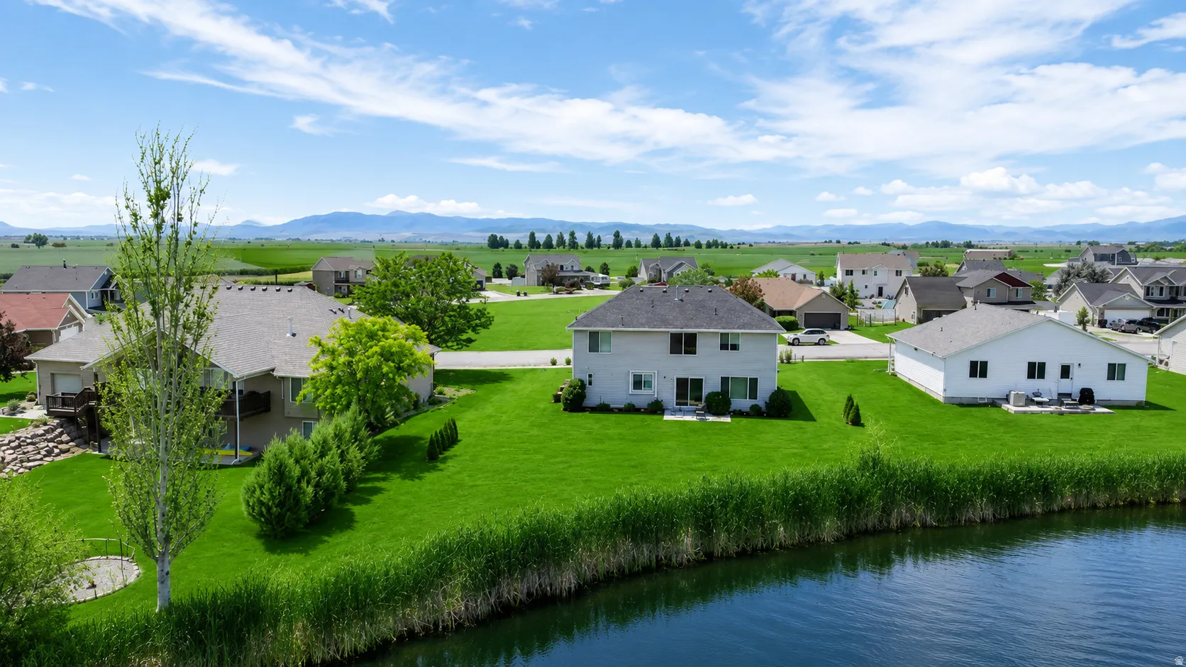 Expansive green lawn bordering a body of water with distant mountains