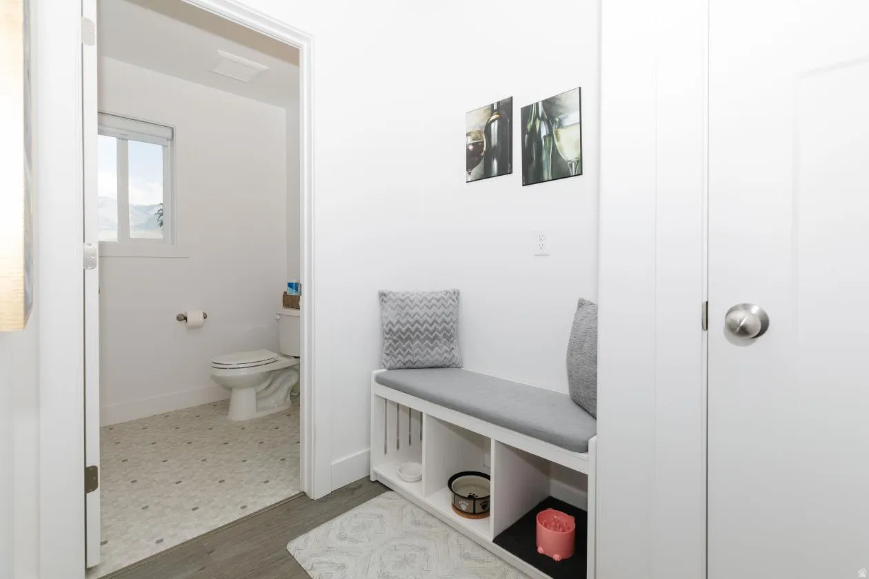 Spacious bathroom featuring a toilet, a window with exterior views, and patterned tile flooring right off of kitchen with a 1\2 bath