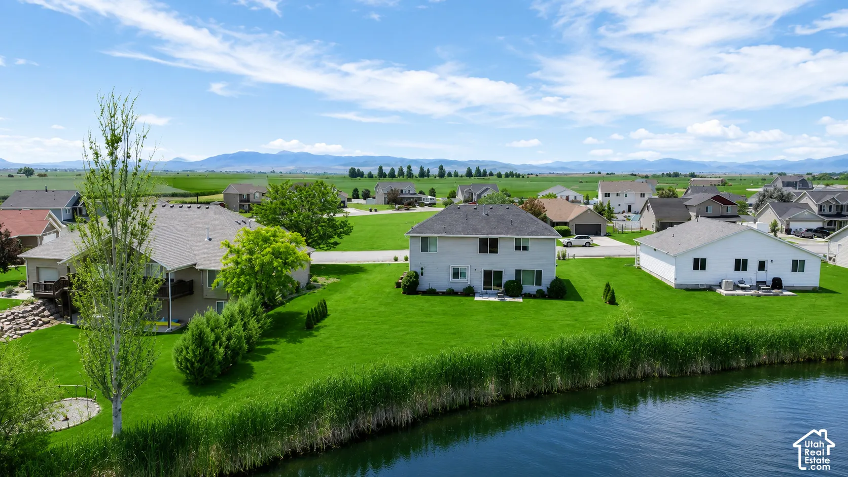 Expansive green lawn bordering a body of water with distant mountains