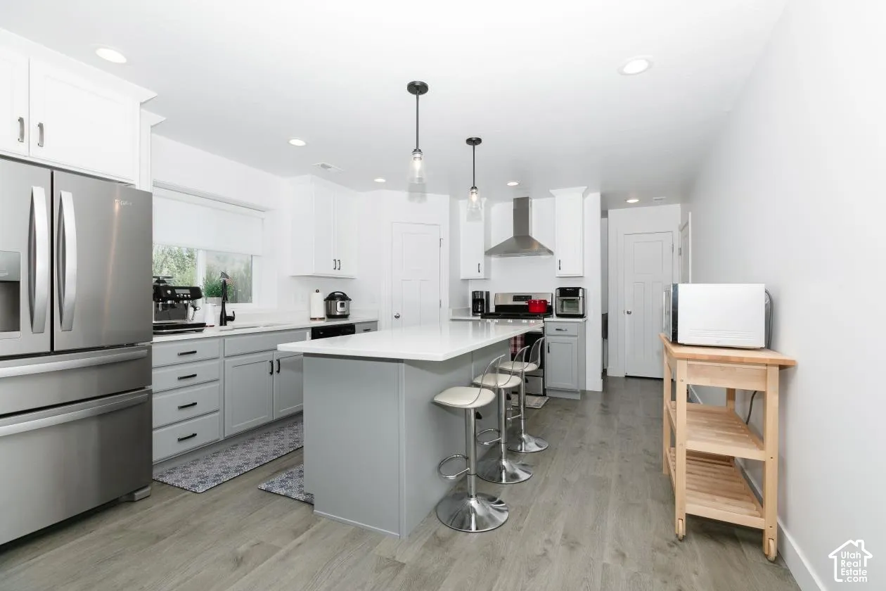 Bright kitchen featuring wood-finish flooring and a central island with countertop seating