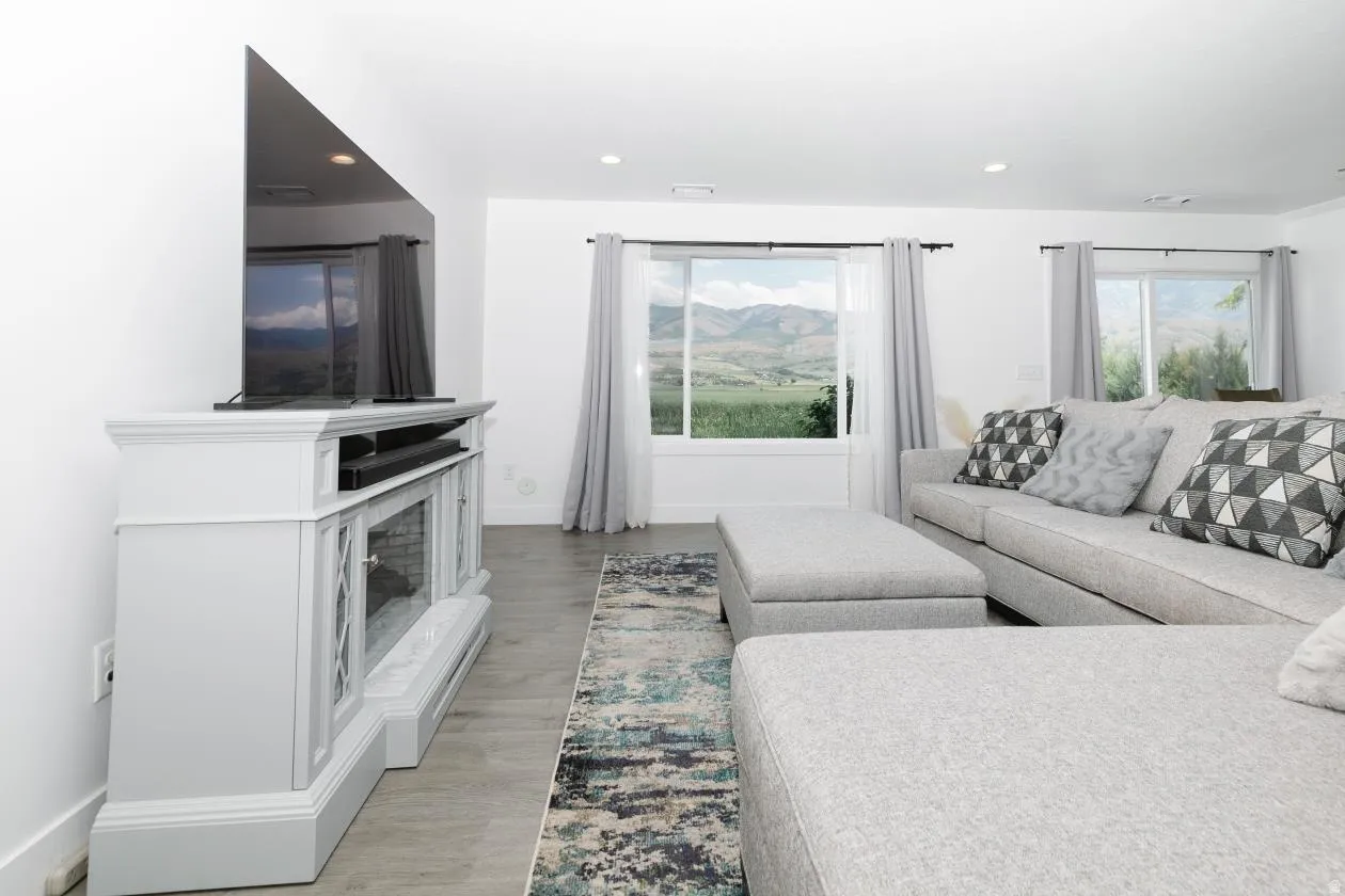 Bright living space featuring expansive windows, wood-finish flooring, recessed lighting, and a decorative fireplace console
