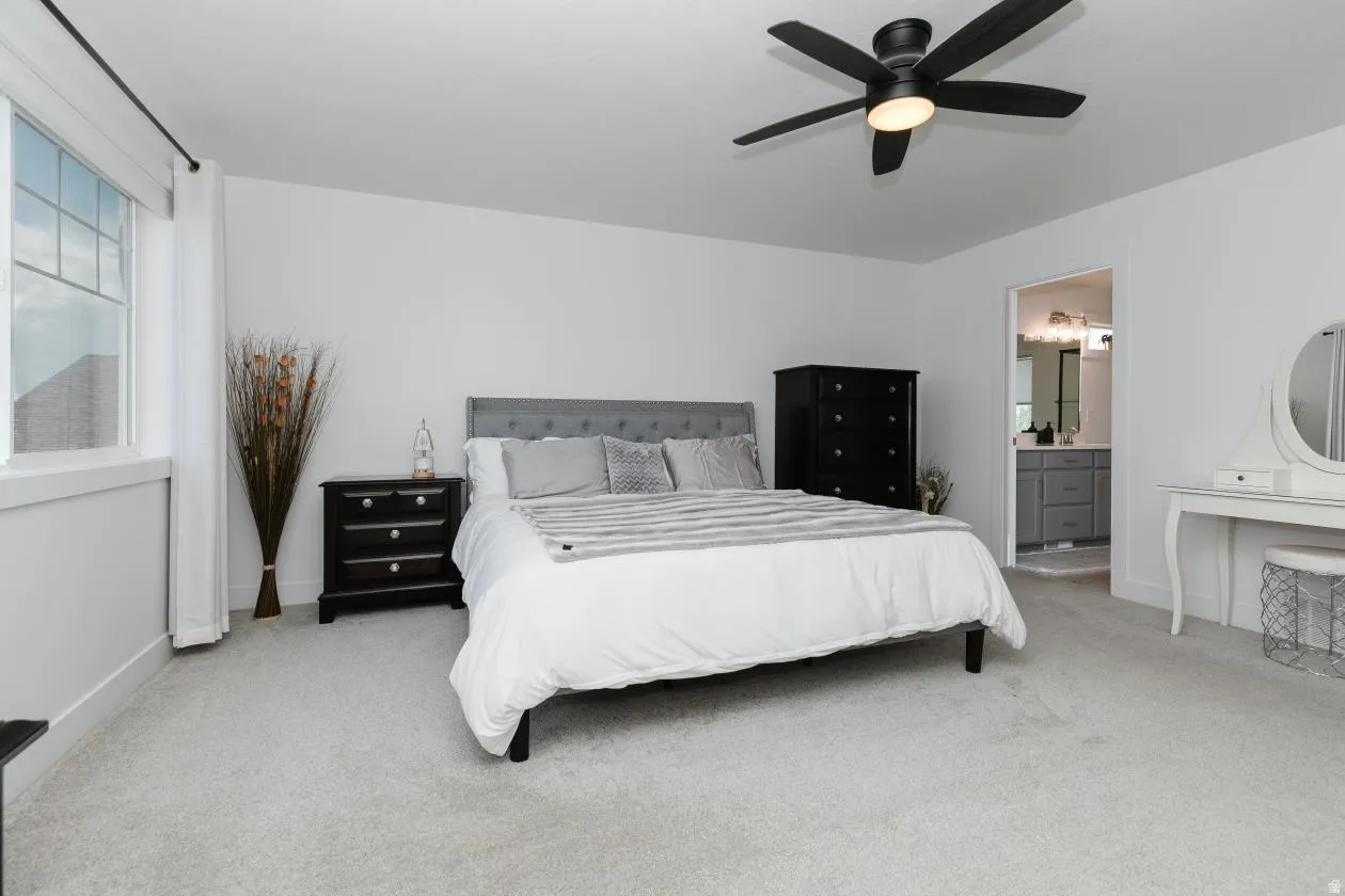 Spacious bedroom with light gray carpeting and white walls