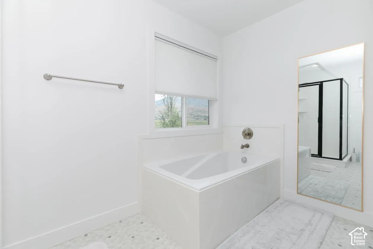 White-tiled bath with a chrome faucet and a window featuring a white blind