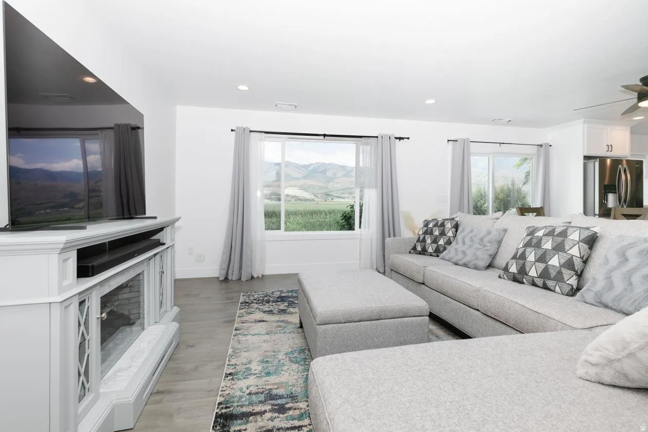 Living area with a  electric fireplace and media console, large windows, lots of light