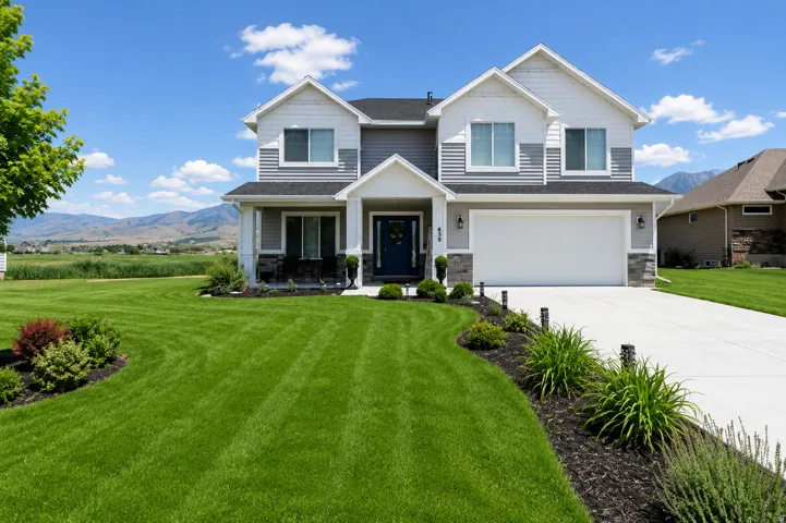 Two-story residence featuring a gray and white exterior with stone accents