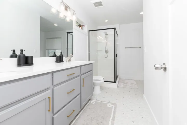 Dual sink vanity with light gray cabinetry and gold-tone hardware
