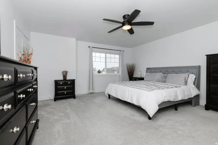 Spacious bedroom featuring light gray carpeting, crisp white walls, and a multi-pane window with white trim