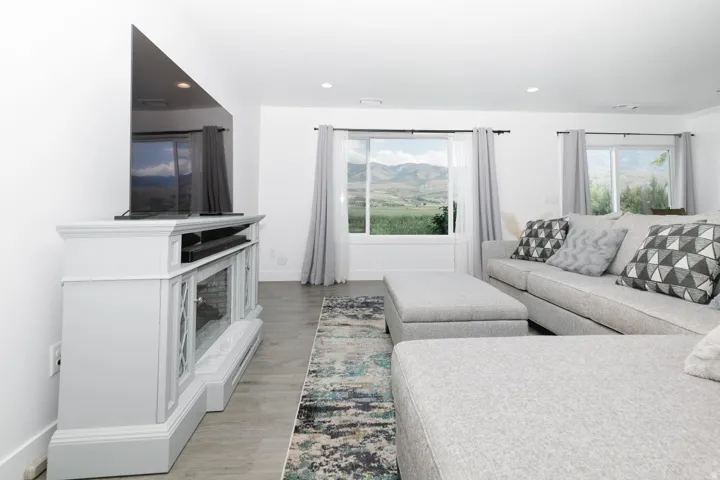 Bright living space featuring expansive windows, wood-finish flooring, recessed lighting, and a decorative fireplace console