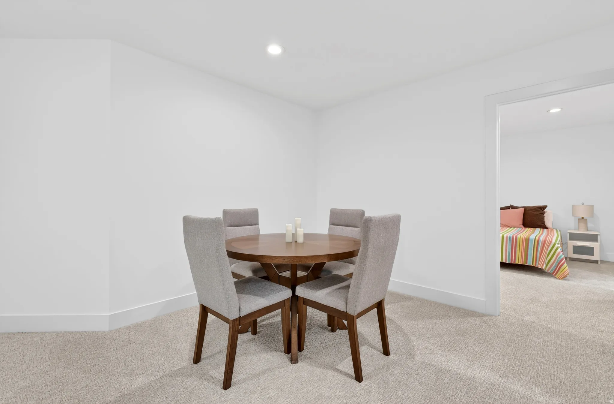 Recessed ceiling light illuminates a carpeted room featuring white walls and white baseboards