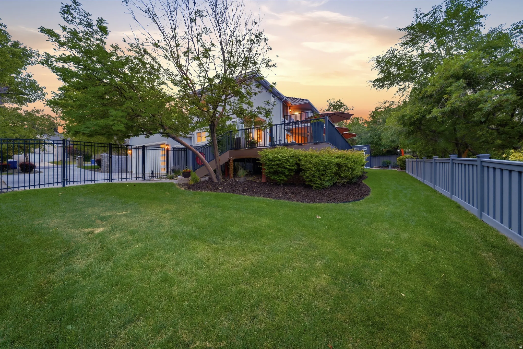 Expansive lawn area with a black metal fence and a tall privacy fence