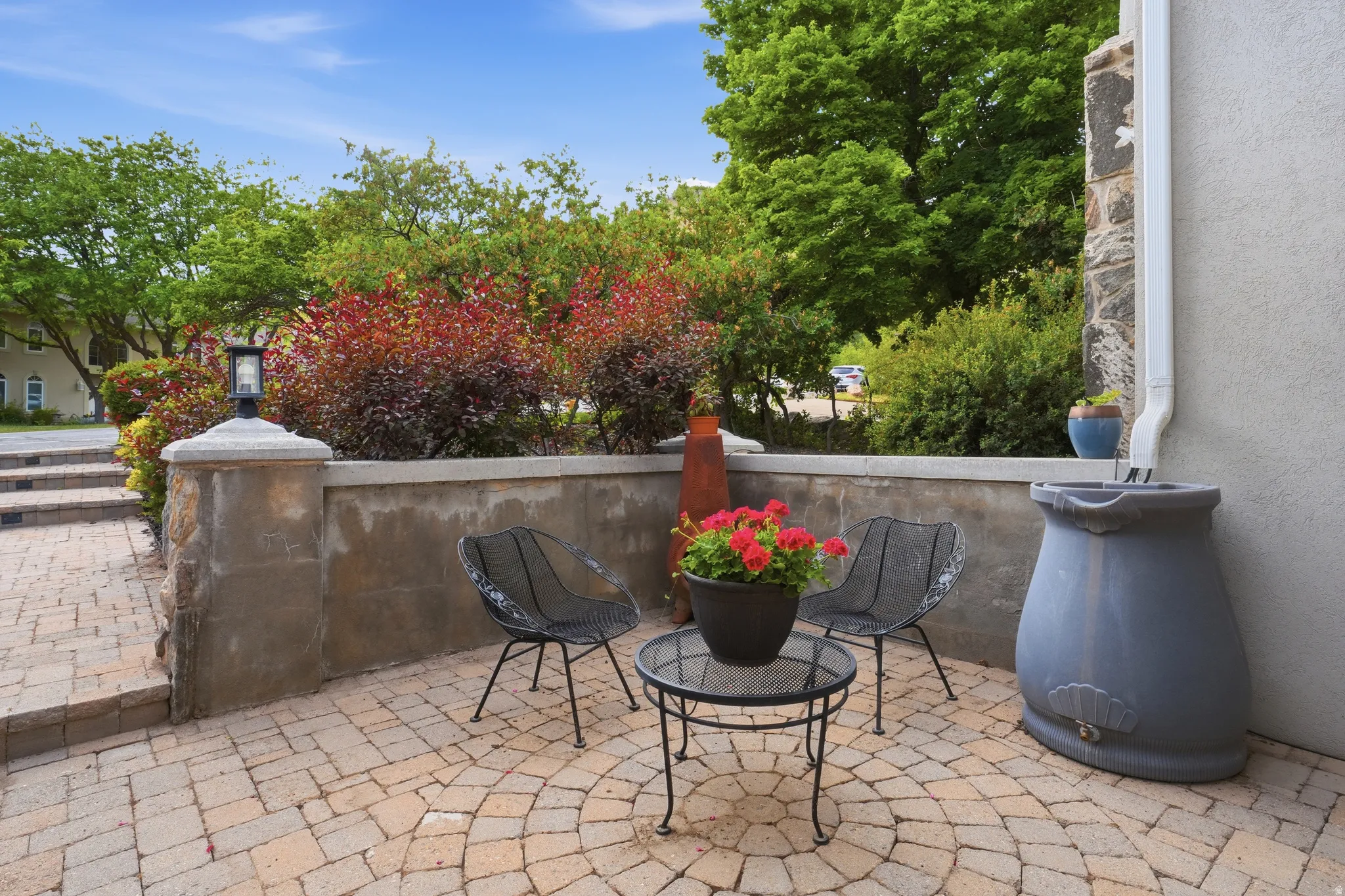 Paver patio featuring a radial pattern, stone retaining wall, and built-in capstone lighting