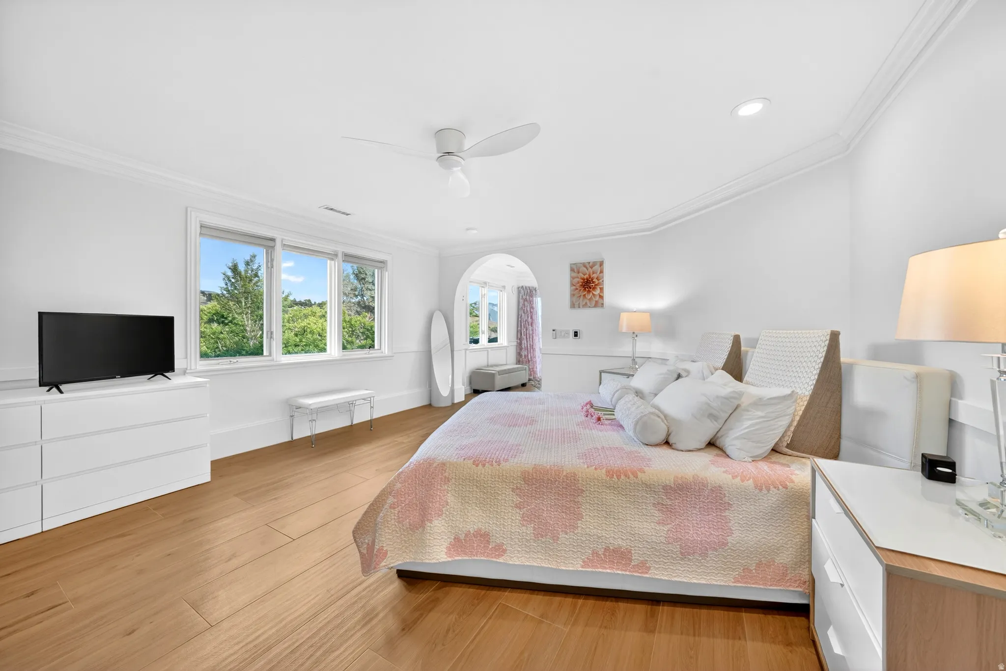 Spacious interior featuring wood-finish flooring, white walls, and crown molding