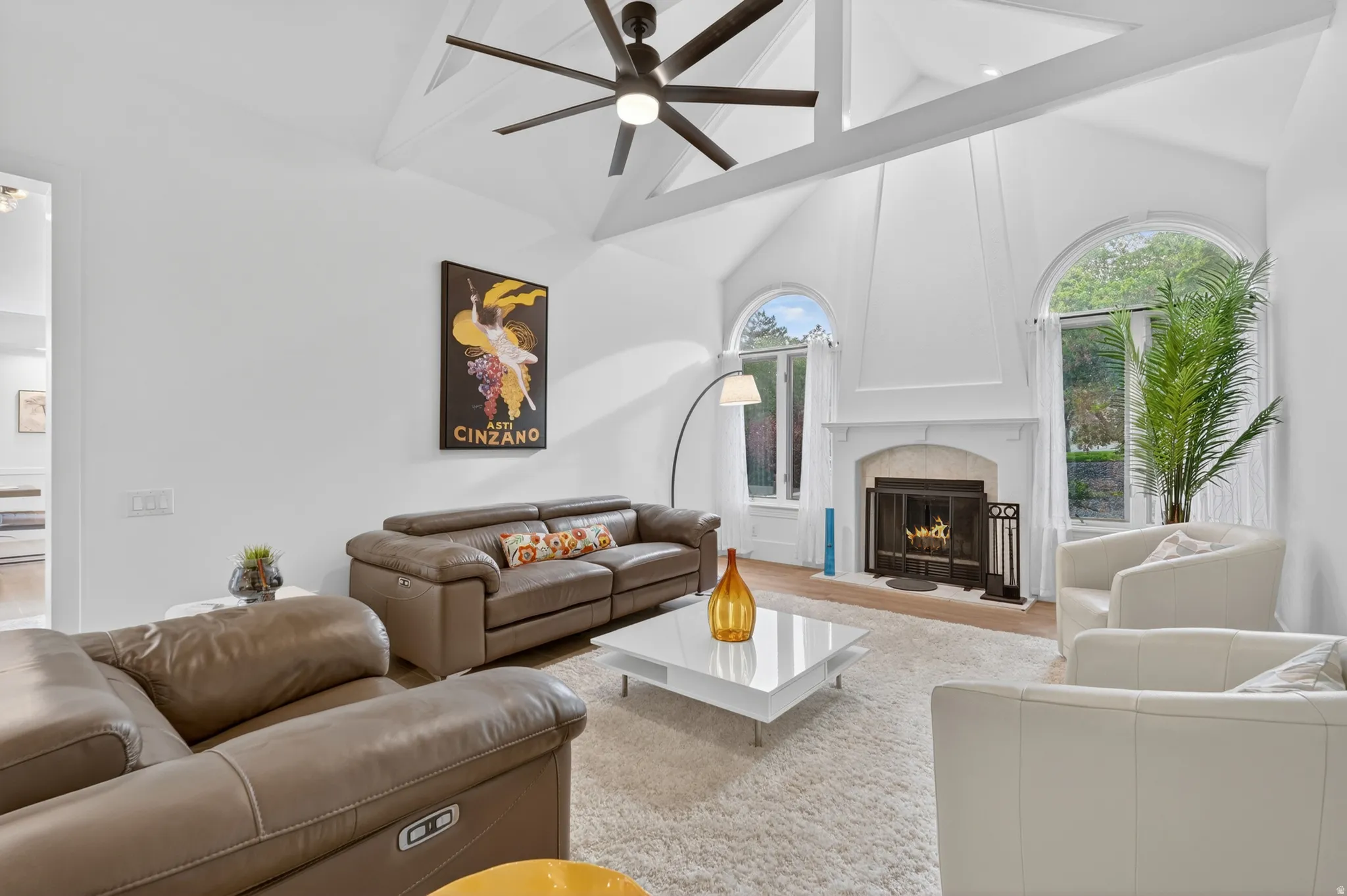 Great room featuring a vaulted ceiling with exposed beams, a ceiling fan, and arched windows